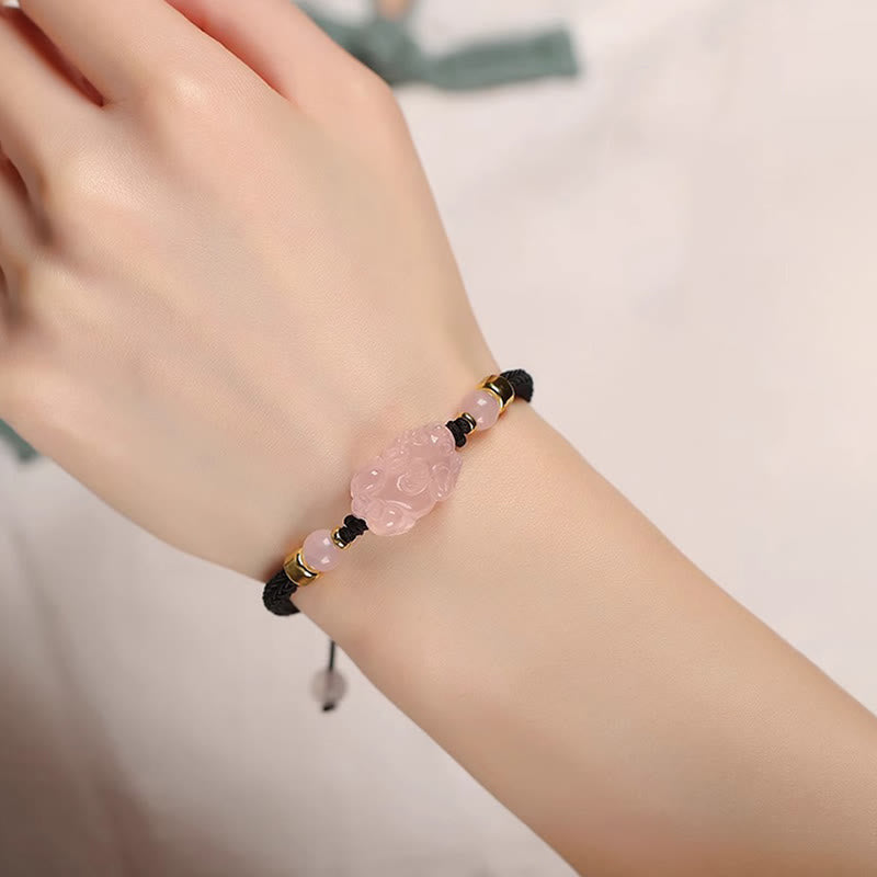 Pink Crystal PiXiu Bracelet – Black cord bracelet on wrist with white fabric background