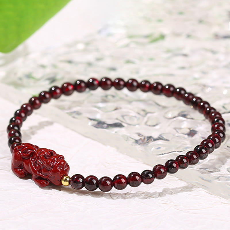 Garnet Cinnabar PiXiu Bracelet – clear glass sheet green beneath white surface, garnet bead detail shot