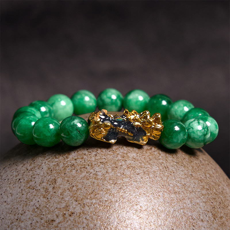 PiXiu Jade Bracelet – Resting on textured stone with dark background, green jade protection