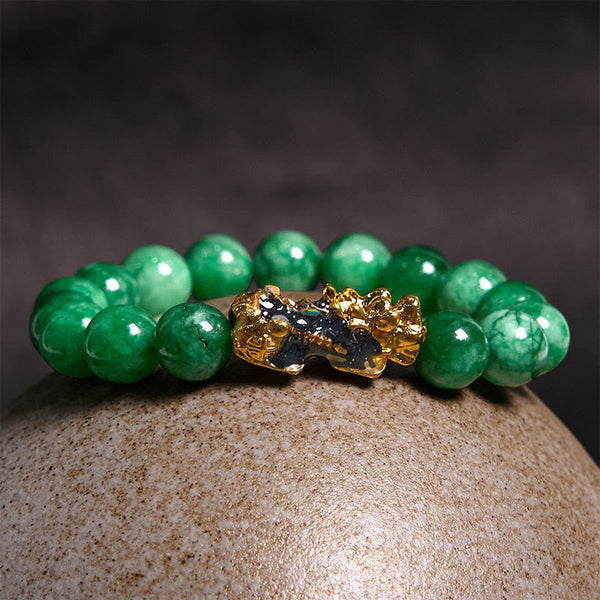 PiXiu Jade Bracelet – Resting on textured stone with dark background, green jade protection