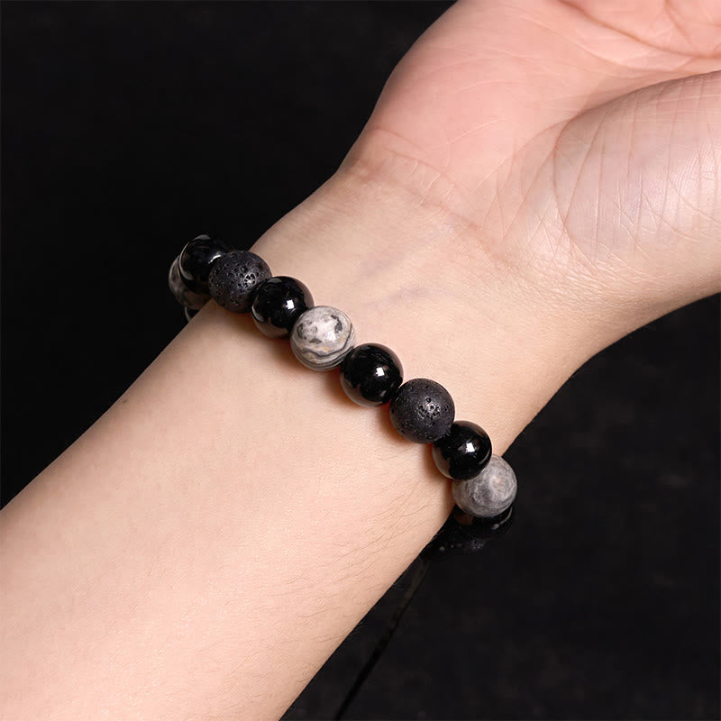 Black Obsidian Lava Rock Yin Yang Bracelet - worn on inner wrist, black background, mixed bead textures