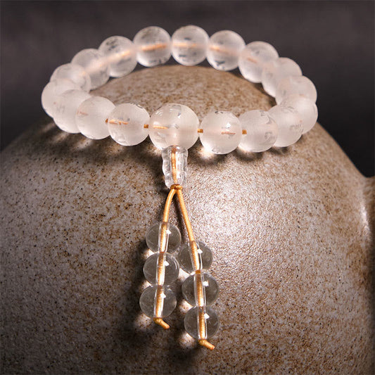 Om Mani Padme Hum Bracelet - Frosted crystal beads on gold cord with tassel against dark backdrop, mala bracelet