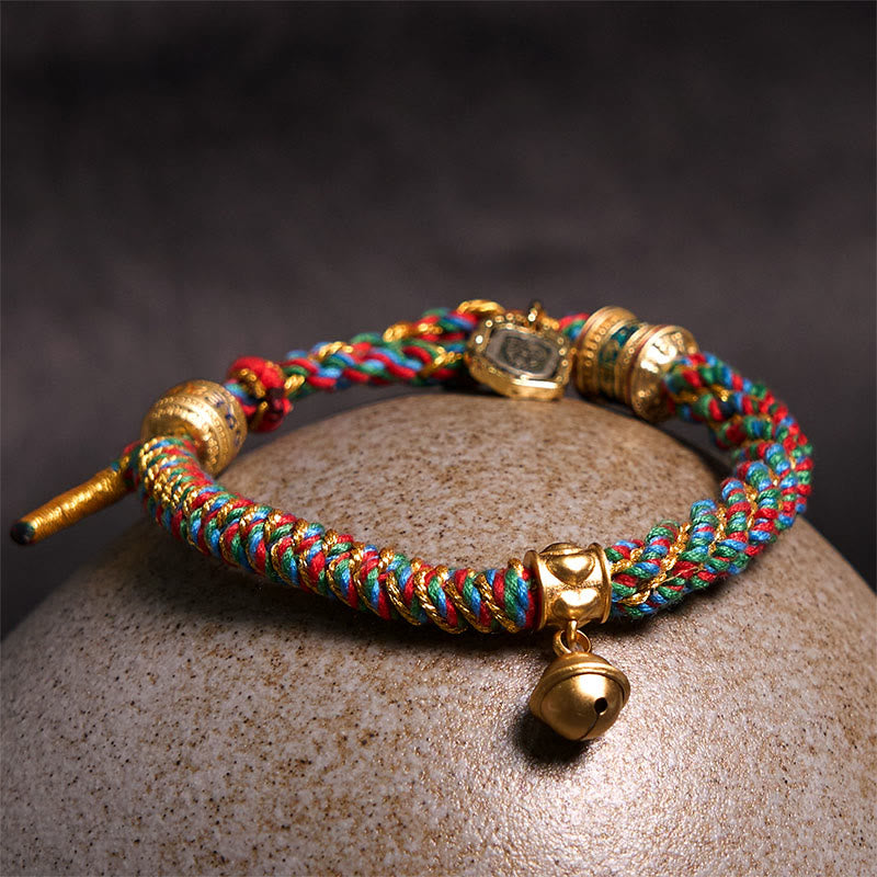 Zakiram Om Mani Padme Hum Charm Bracelet – Resting on river stone with gold accents visible, woven blessing bracelet
