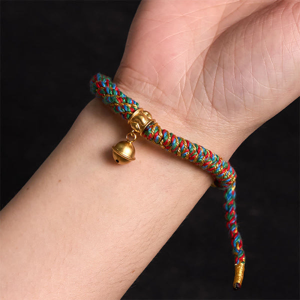Zakiram Om Mani Padme Hum Charm Bracelet – Worn on wrist showing colorful braid and gold bell, close-up fit view