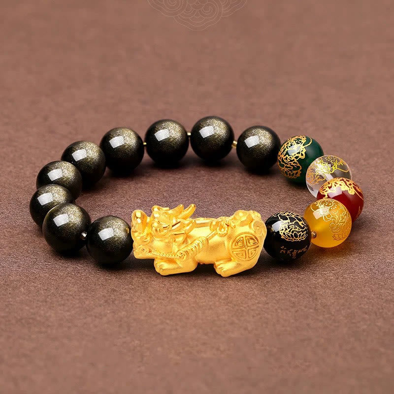 Gold Sheen Obsidian PiXiu Bracelet – flat lay on brown fabric, gold PiXiu and black beads, side angle view
