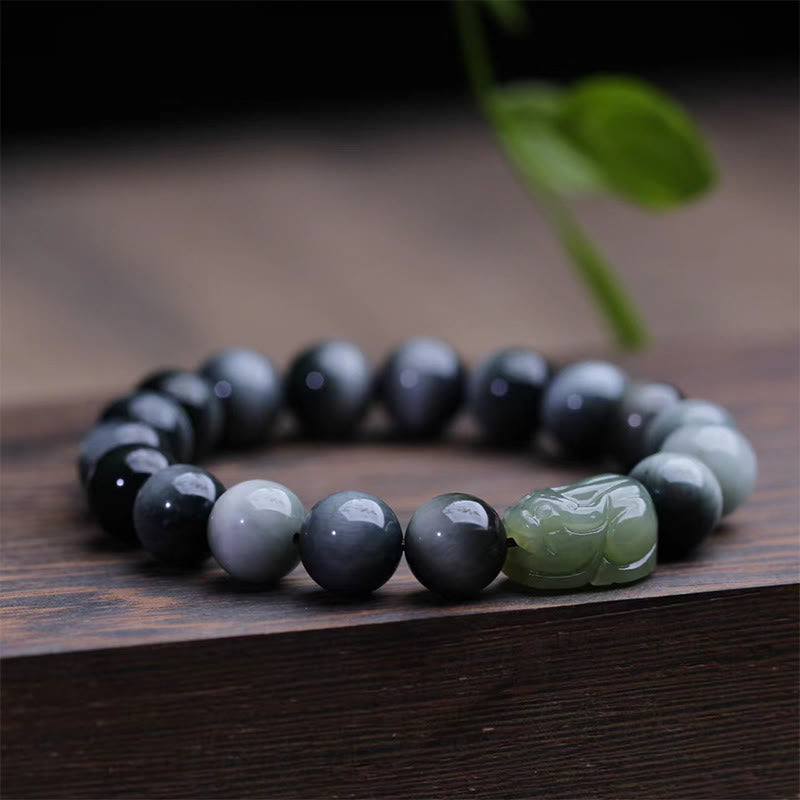 Eagle's Eye Jade PiXiu Bracelet – side view on wooden surface, gray beads with green jade PiXiu, calm energy