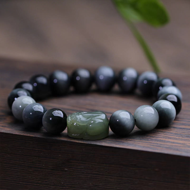 Eagle's Eye Jade PiXiu Bracelet – close-up of gray eagle eye beads and green jade PiXiu on wood, detail shot