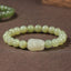Hetian Jade PiXiu Bracelet – light green jade beads with carved PiXiu on brown fabric, front view, fortune jewelry
