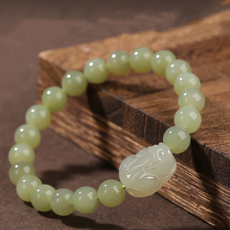 Hetian Jade PiXiu Bracelet – pale green jade bracelet with PiXiu on wooden block, side angle, luck charm