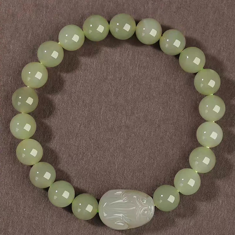Hetian Jade PiXiu Bracelet – top-down view of round green jade beads with PiXiu center, brown background