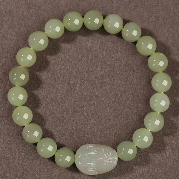 Hetian Jade PiXiu Bracelet – top-down view of round green jade beads with PiXiu center, brown background