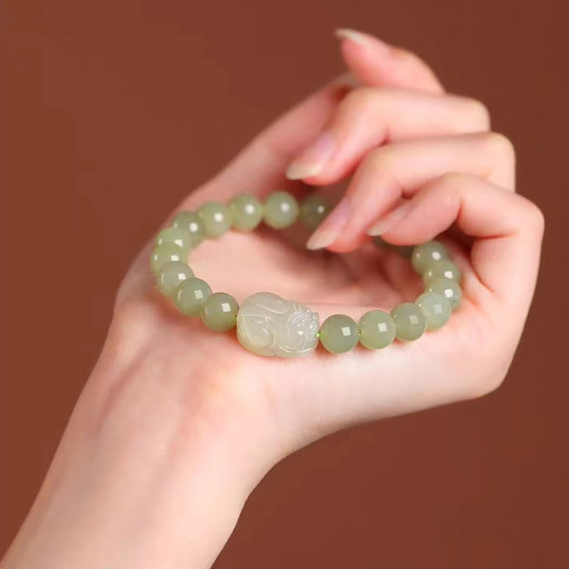 Hetian Jade PiXiu Bracelet – green jade PiXiu bracelet held in palm, warm brown background, luxury gift