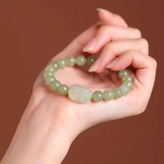 Hetian Jade PiXiu Bracelet – green jade PiXiu bracelet held in palm, warm brown background, luxury gift