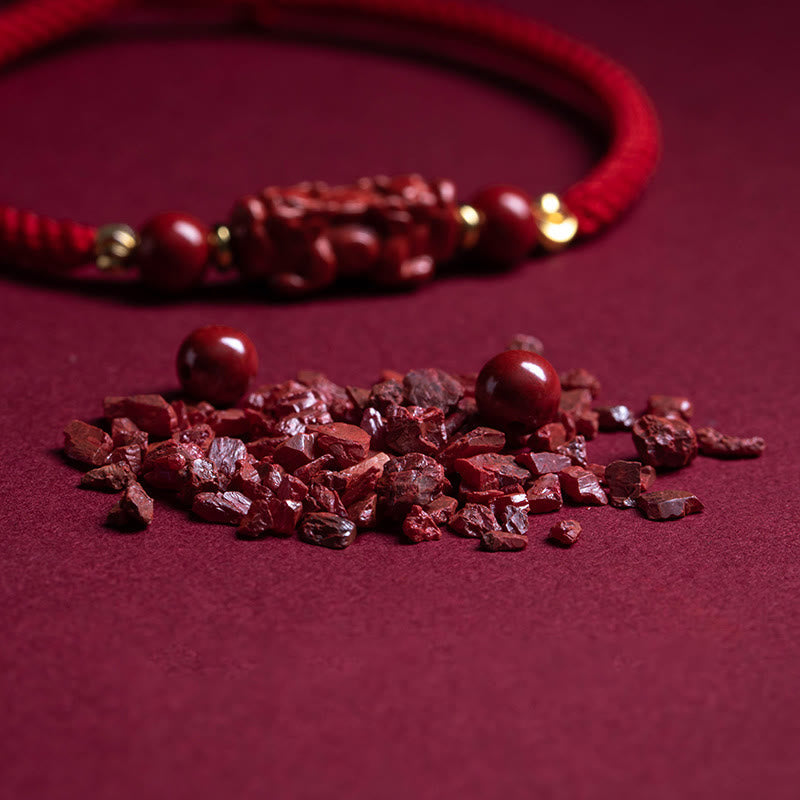 Cinnabar Ruyi Fu PiXiu Red Bracelet – raw cinnabar pieces on red velvet with bracelet blurred, natural stone material