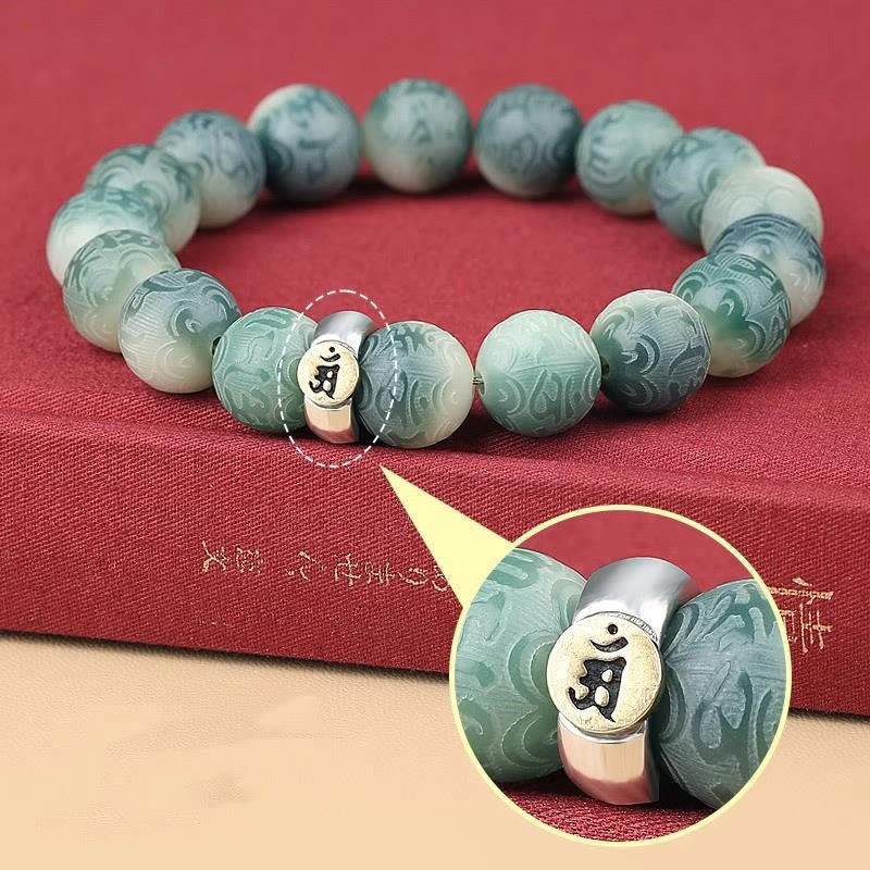 Chinese Zodiac Wisdom Bracelet – Teal jade beads on red fabric, magnified Om symbol on metal spacer