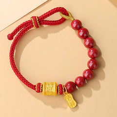 Sterling Silver Cinnabar Bracelet – Top-down view of red beads and braided cord with gold charms, blessing bracelet