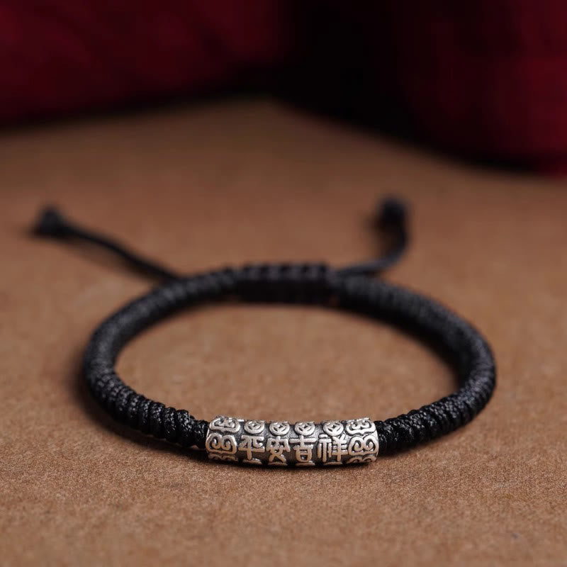 Silver Mantra Rope Bracelet – Black cord variant with silver fortune bead on warm brown surface, unisex bracelet