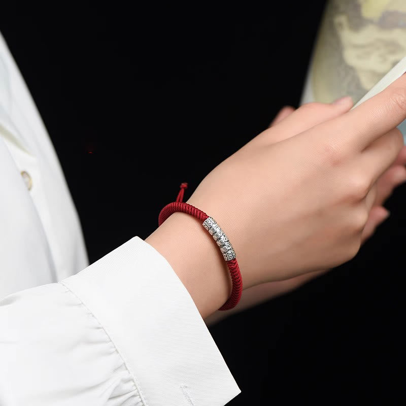 Silver Mantra Rope Bracelet – Red cord with silver mantra bead worn on wrist against black background, spiritual jewelry