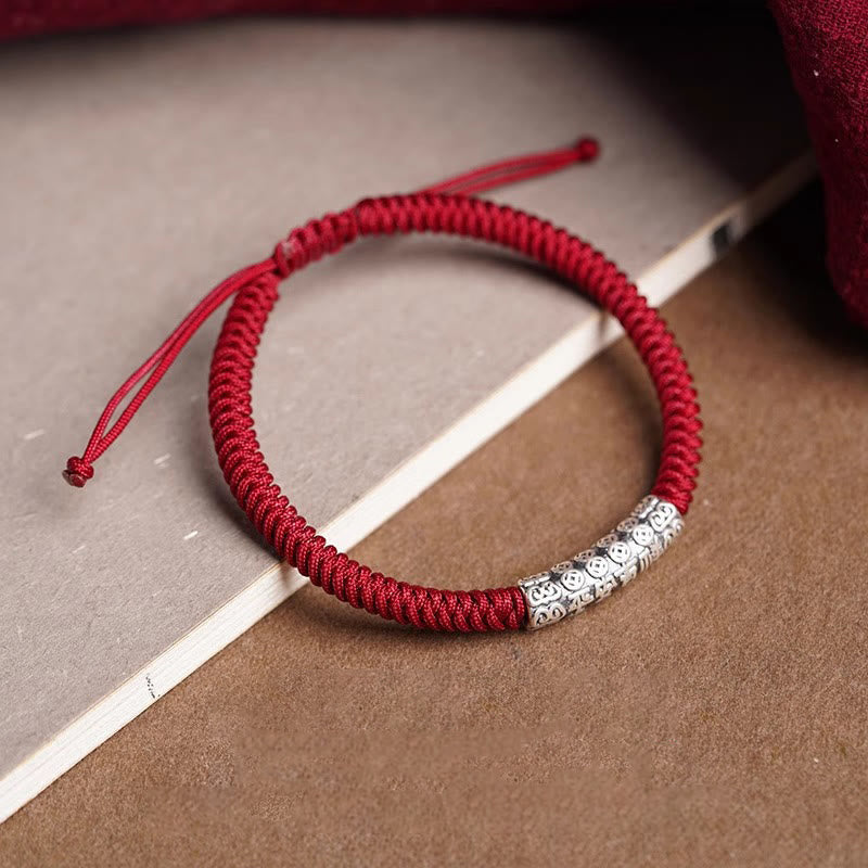 Silver Mantra Rope Bracelet – Red braided cord with silver charm on styled book and fabric setting, fortune bracelet