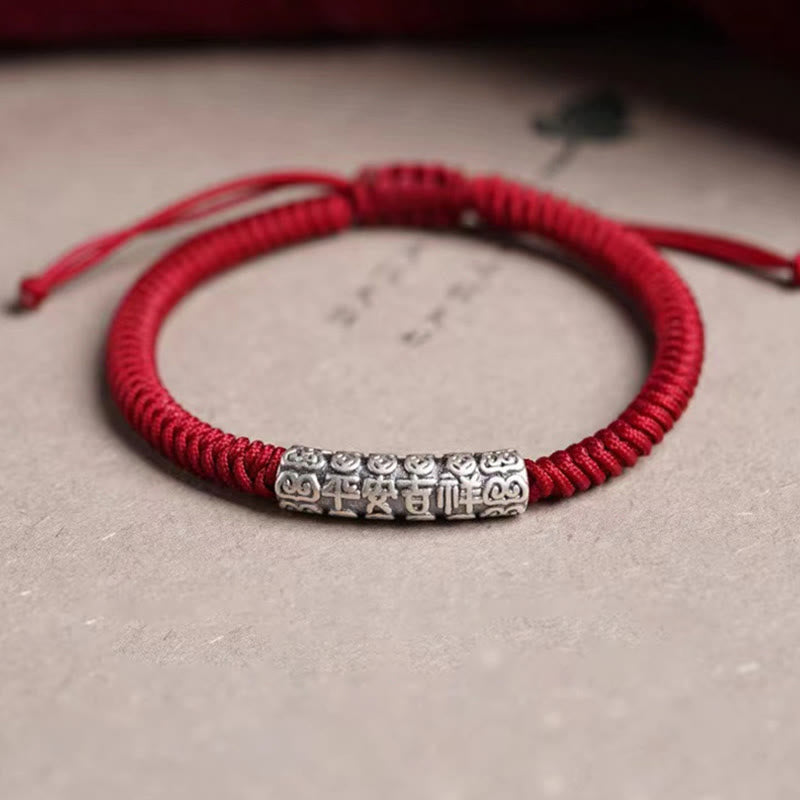 Silver Mantra Rope Bracelet – Red cord with antique silver bead on beige textured background, traditional amulet