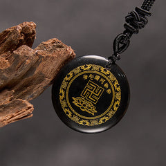 Black Obsidian Purification Pendant - three-quarter view on gray backdrop, black cord with Chinese knot, wood prop, serene