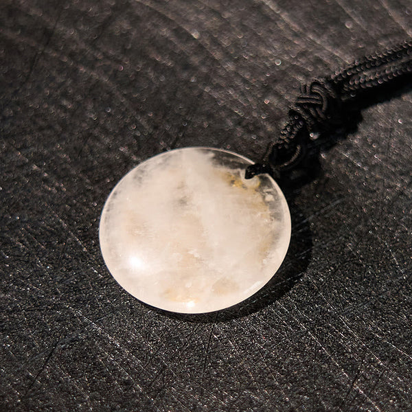 White Crystal Purification Pendant - macro detail of translucent stone natural inclusions, dark woven fabric, luminous