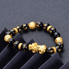 Black Obsidian PiXiu Om Mani Padme Hum Bracelet – on dark surface with black geometric props, side angle, feng shui bracelet