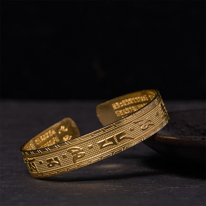 Om Mani Padme Hum Copper Brass Bangle – Dramatic lighting on dark surface, gold finish