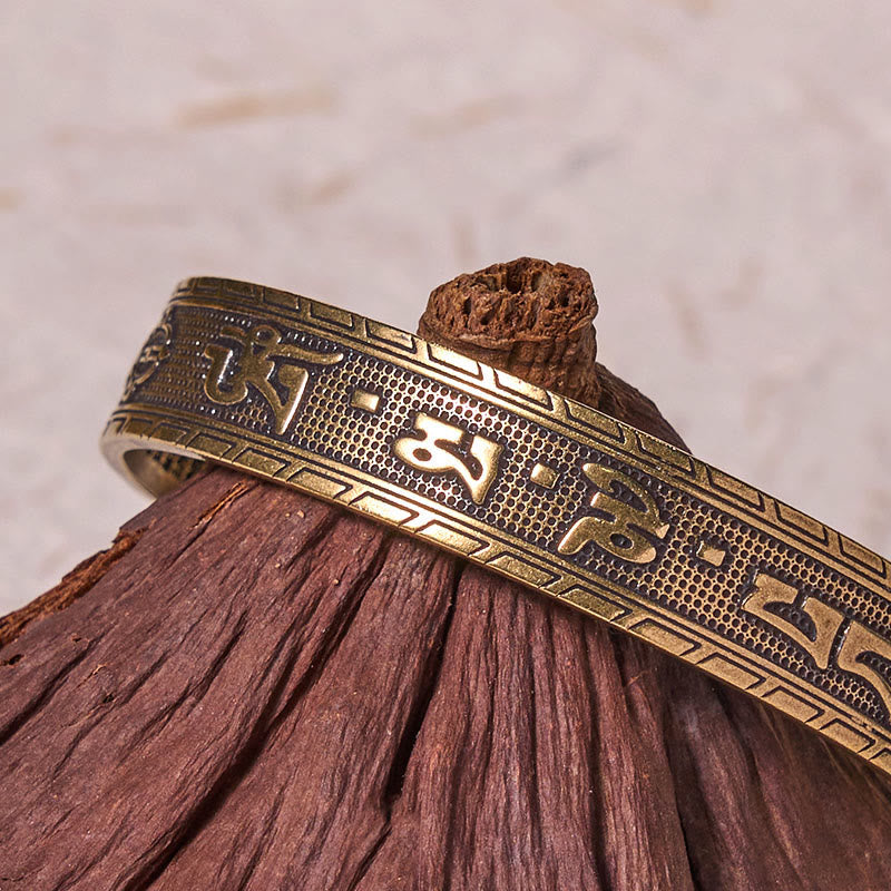 Om Mani Padme Hum Copper Brass Bangle – Macro shot on driftwood, raised mantra relief