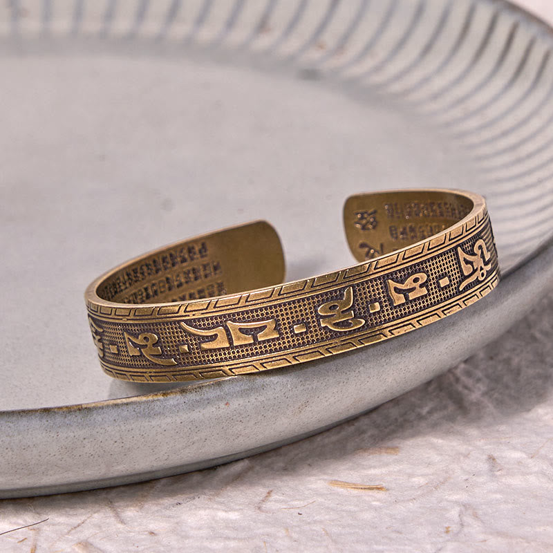 Om Mani Padme Hum Copper Brass Bangle – On ceramic plate with linen backdrop, copper tones