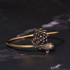 Lotus Koi Fish Copper Brass Luck Bangle – open cuff with sculpted lotus and koi with red eye, 45 angle on dark stone