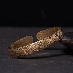 Dragon Phoenix Copper Brass Bracelet – Three-quarter view on dark stone, engraved dragon and phoenix relief, Protective