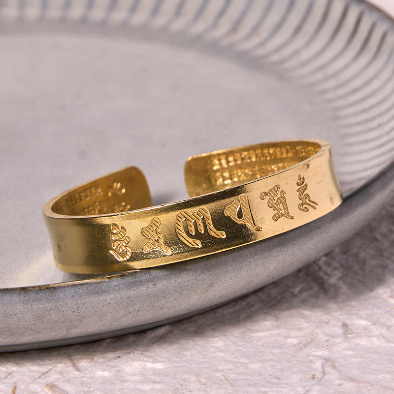 Om Mani Padme Hum Copper Cuff Bangle – Displayed on gray ceramic dish, warm gold tones