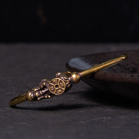 PiXiu Copper Bangle – Antique brass cuff with PiXiu and compass charm on dark plate side view Main image