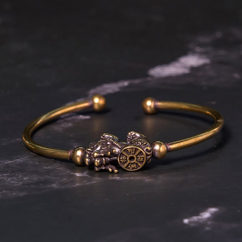 PiXiu Copper Bangle – Open cuff brass bracelet with PiXiu compass on black marble surface