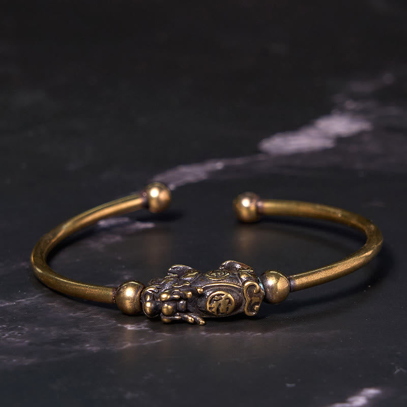 PiXiu Copper Bangle – Brass open cuff with ornate PiXiu compass on black marble