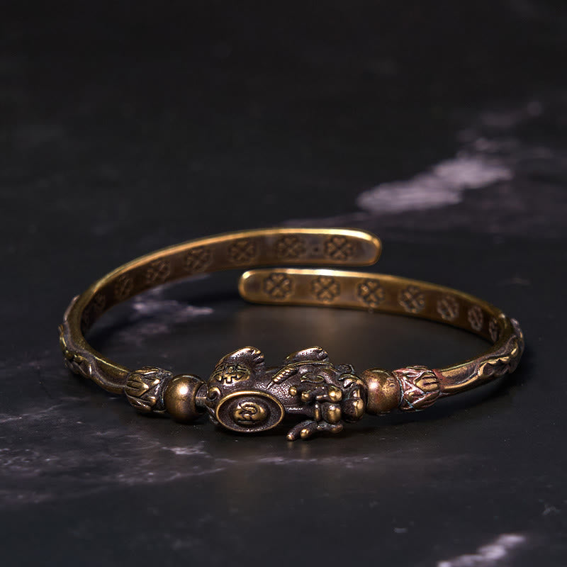 PiXiu Coin Bangle – Antique brass bangle with PiXiu coin on black marble surface
