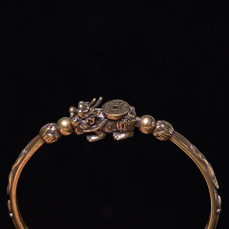 PiXiu Coin Bangle – Close-up of PiXiu coin motif on brass cuff against black backdrop