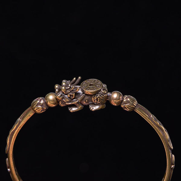 PiXiu Coin Bangle – Close-up of PiXiu coin motif on brass cuff against black backdrop