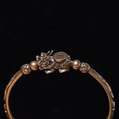 PiXiu Coin Bangle – Close-up of PiXiu coin motif on brass cuff against black backdrop