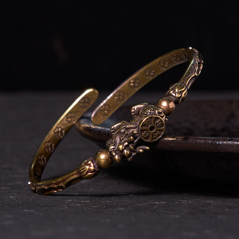 PiXiu Coin Bangle – Two stacked antique brass cuffs with PiXiu coin detail on dark surface