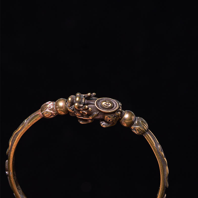 PiXiu Coin Bangle – Detailed top view of PiXiu holding coin on brass cuff black bg