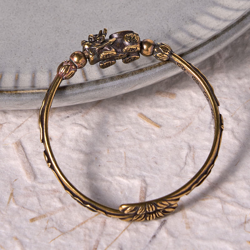 PiXiu Coin Bangle – Brass cuff with PiXiu coin detail on gray ceramic dish