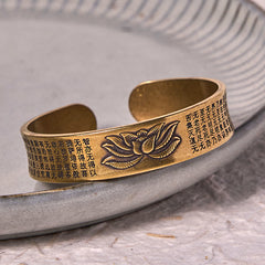 Heart Sutra Lotus Copper Brass Peace Cuff Bracelet – brass cuff with lotus on gray ceramic dish, mindful calm