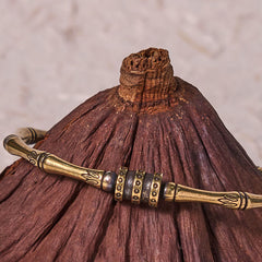 Bamboo Lotus Copper Brass Bracelet Bangle – rustic bamboo cuff with tribal engravings on natural wood stand, earthy elegance