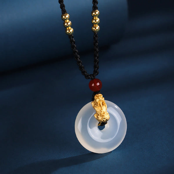 Black Onyx Agate Peace Buckle PiXiu Necklace – white agate peace buckle with gold PiXiu red bead, blue fabric background
