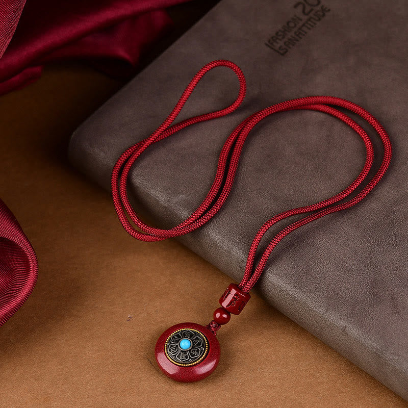 Natural Cinnabar Om Mani Padme Hum Pendant – S-curve drape on textured surface with turquoise center, cinnabar amulet
