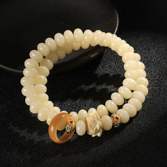 Bodhi Seed Lotus Bracelet – coiled cream beads with carved floral charm and amber ring, spiritual elegance