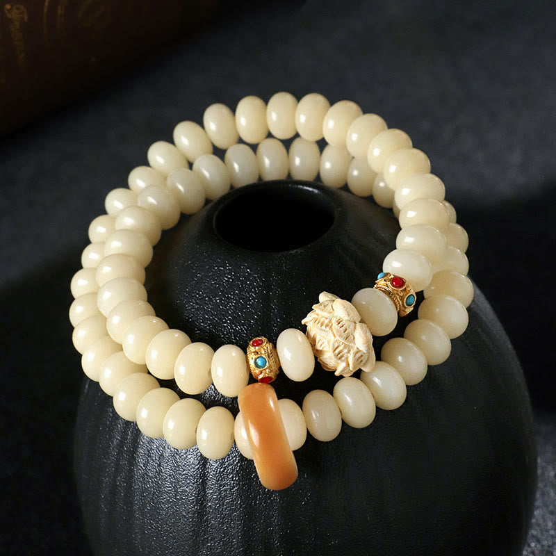 Bodhi Seed Lotus Bracelet – draped on black ceramic vessel with carved guardian charm and amber drop, zen decor