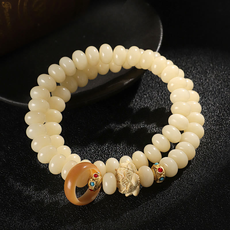 Bodhi Seed Lotus Bracelet – relaxed loop on dark fabric showing carved centerpiece and warm amber ring, wisdom charm